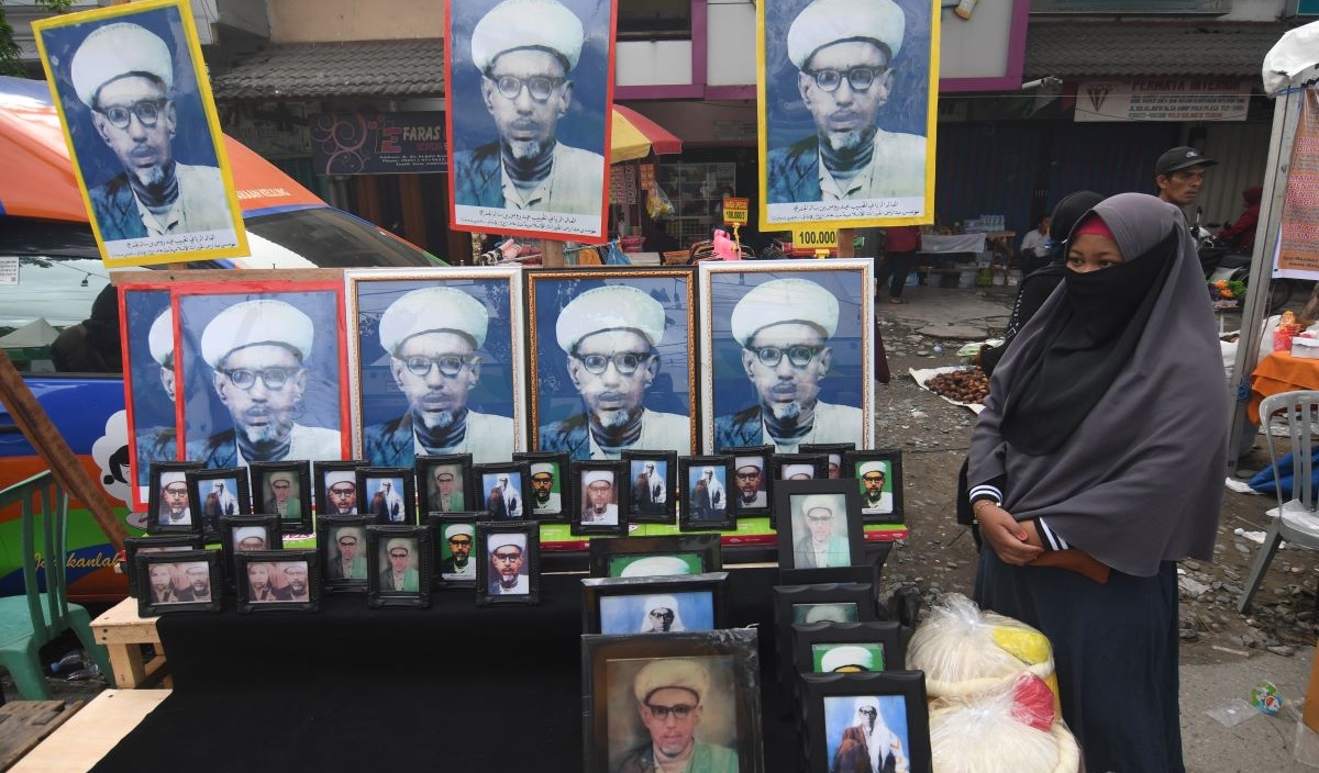 Warga menjual foto Sayyid Idrus bin Salim Aljufri atau Guru Tua pada peringatan Haul Guru Tua di Kompleks Alkhairaat di Palu, Sultra.