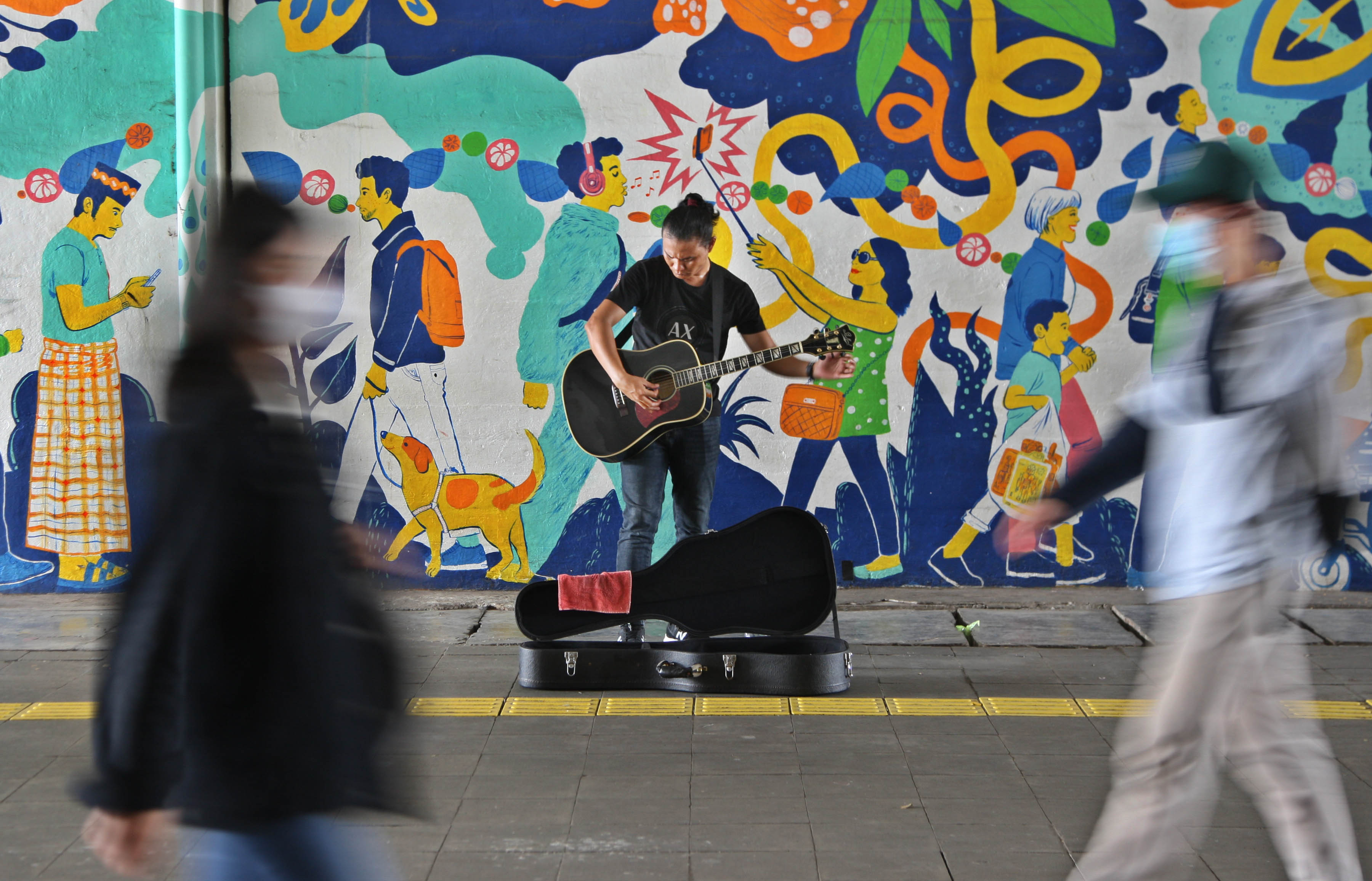Seorang pengamen tengah beraksi di jalur pejalan kaki di Terowongan Kendal, Menteng, Jakarta