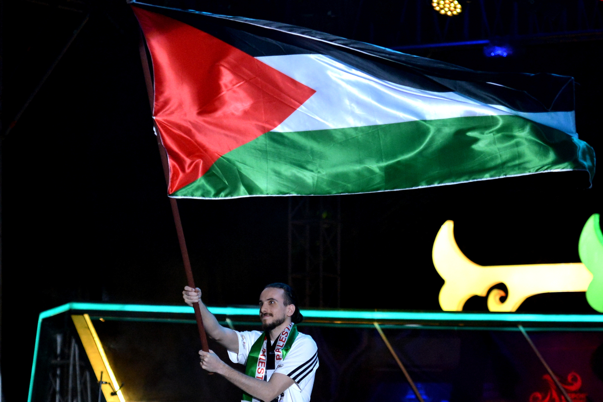 Atlet esport asal Palestina mengibarkan bendera saat defile atlet dalam pembukaan International Esports Federation