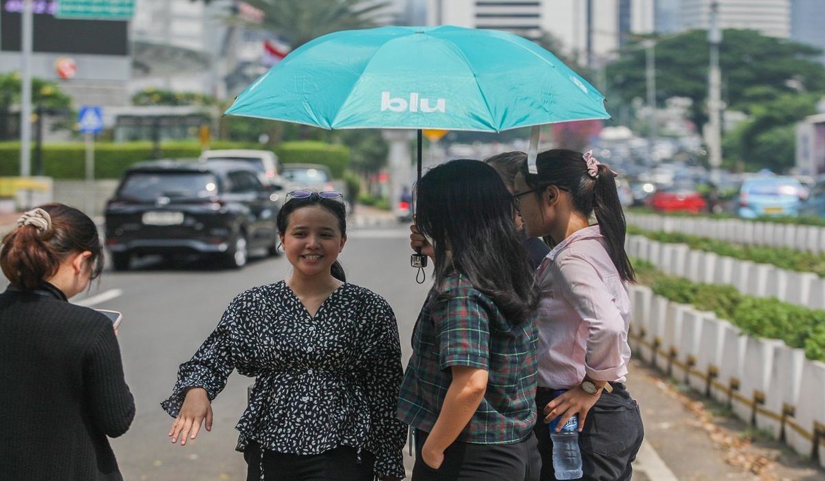 Para pejalan kaki membawa payung untuk melindungi dari dari suhu panas matahari di kawasan Tosari, Jakarta.