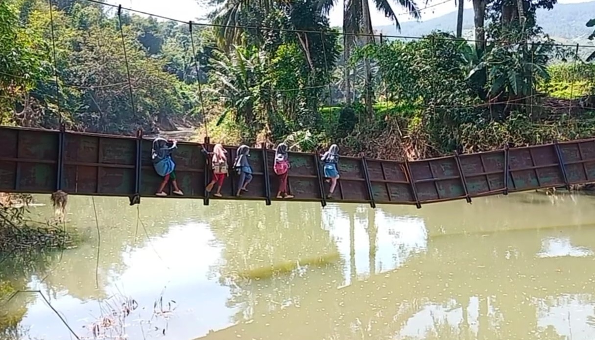 Sejumlah anak di Sukabumi nekat melintasi sungai di atas jembatan yang rusak parah. 