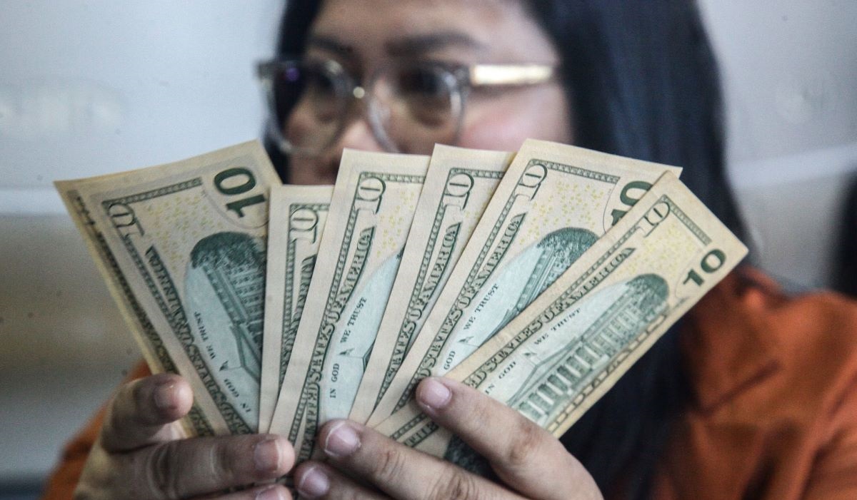 Petugas menghitung uang pecahan dolar AS dan rupiah di gerai jasa penukaran mata uang asing, Menteng, Jakarta Pusat, Kamis (20/6/2024).