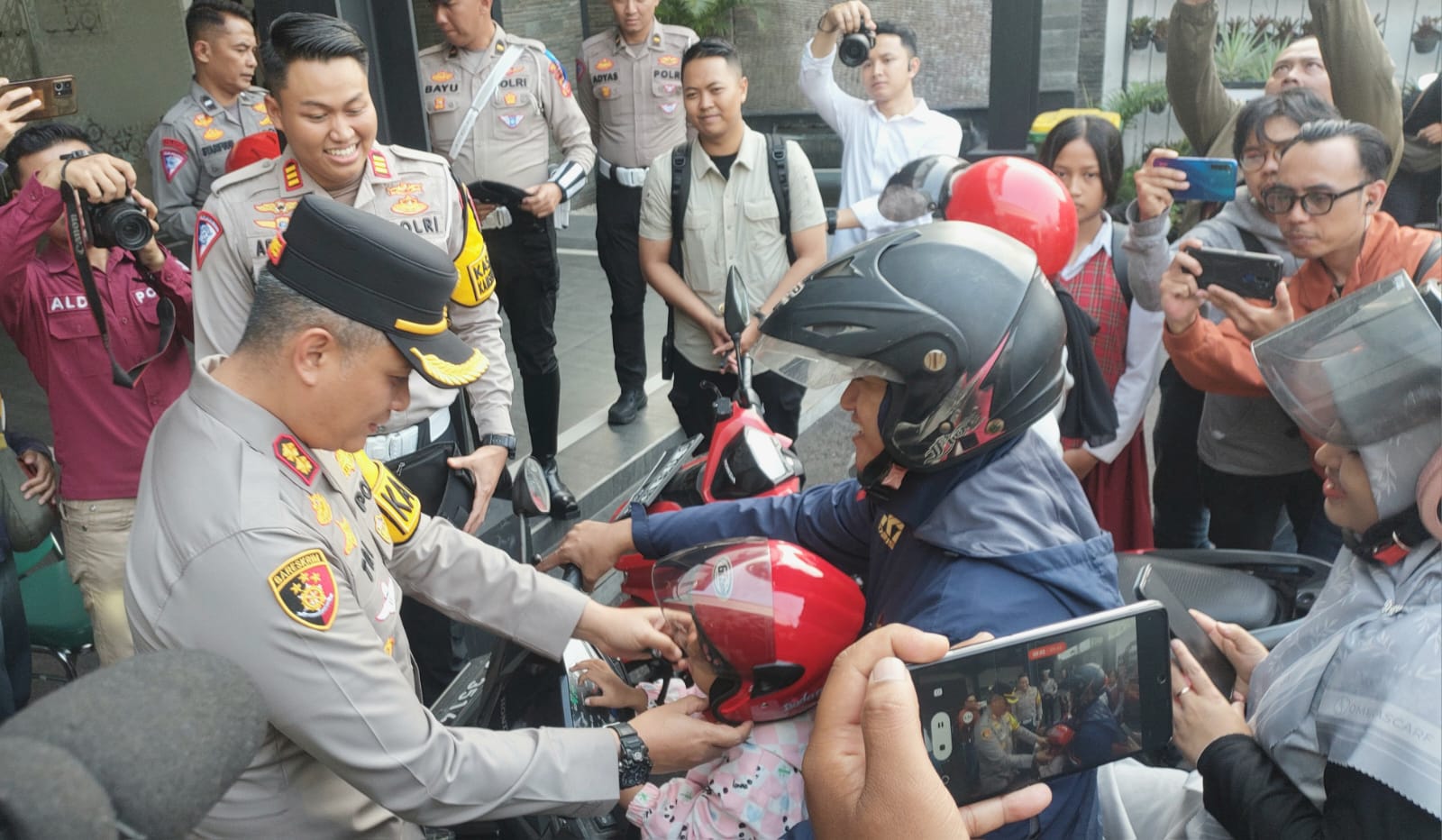 Kapolres Cimahi AKB Tri Suhartanto memasangkan helm pada pengendara sepeda motor. 