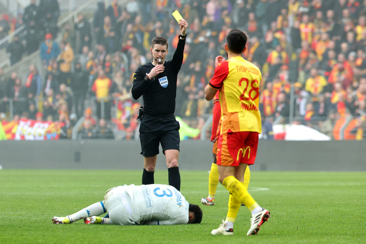 Wasit Prancis Francois Letexier memberikan kartu kuning kepada gelandang Prancis Lens #28 Adrien Thomasson (kanan) selama pertandingan sepak