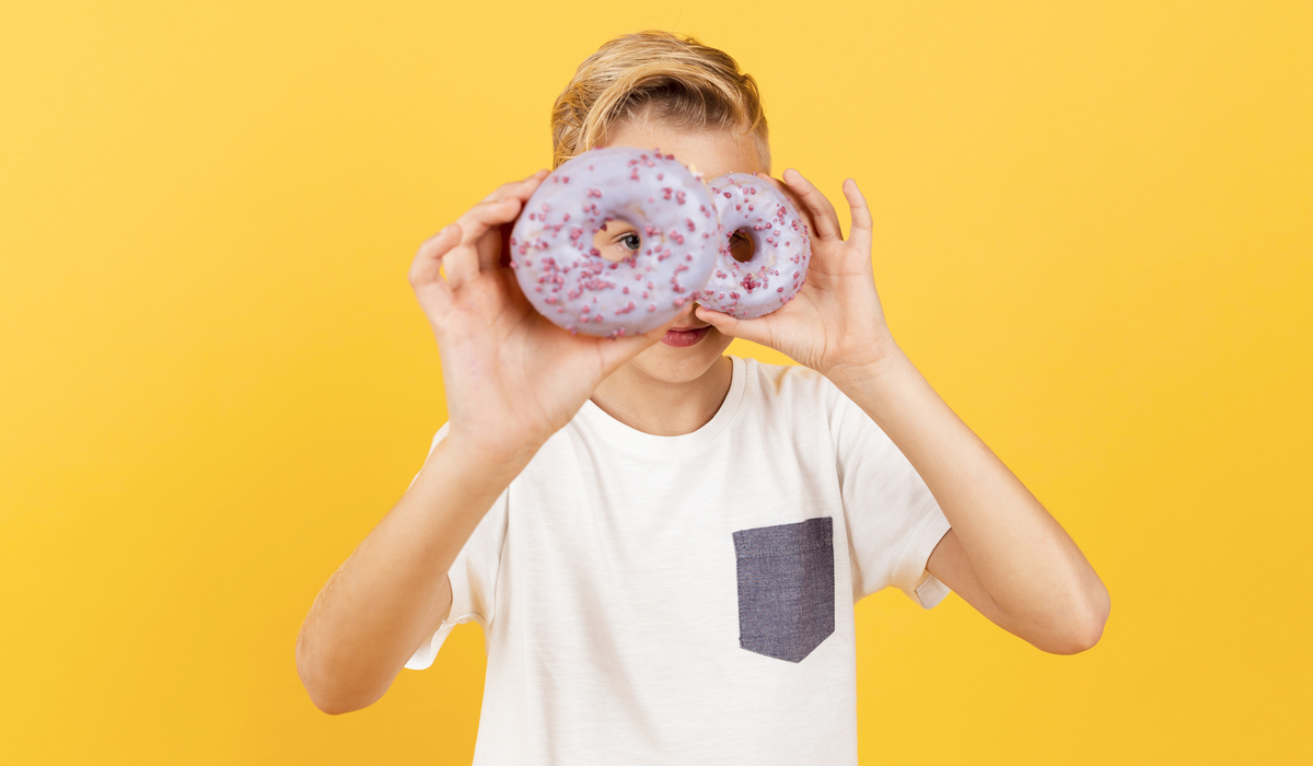 Ilustrasi, seorang anak memegang donat, salah satu jenis makanan manis yang berpotensi sebabkan diabetes anak.