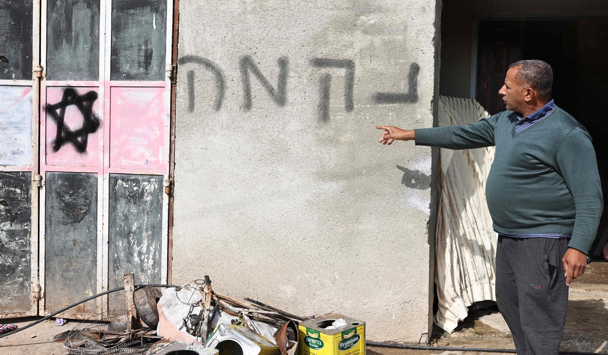 Seorang warga Palestina menunjuk Bintang Daud dan ancaman dalam bahasa Yahudi usai pemukin Israel menyerbu Tepi Barat.