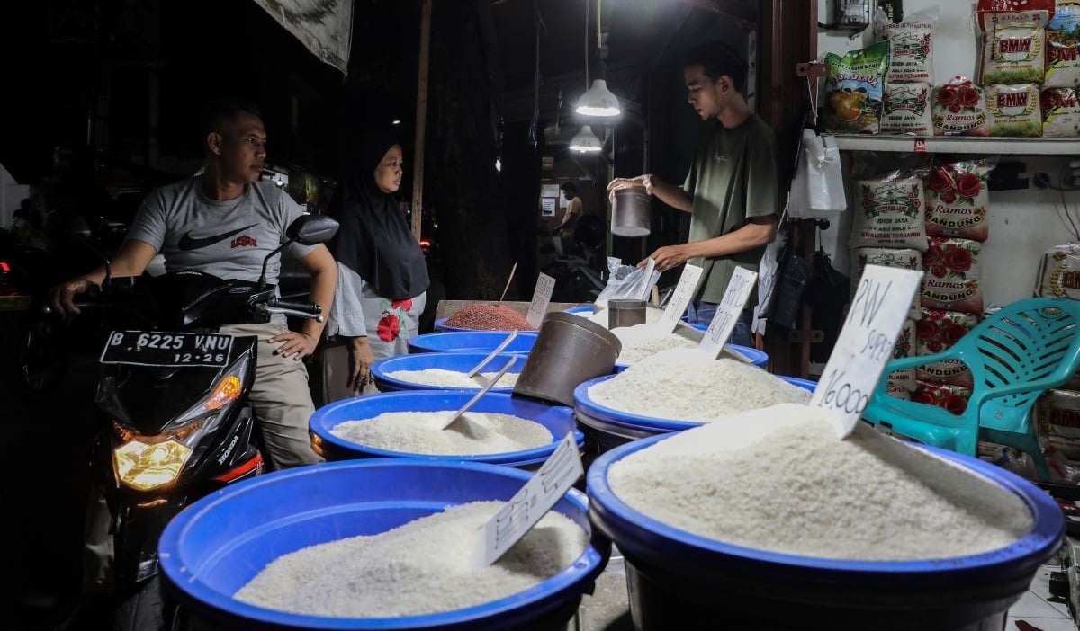 Pedagang melayani pembeli di kios penjualan beras medium dan premium kawasan Petukangan Utara, Jakarta Selatan, Senin (26/2/2024) malam.