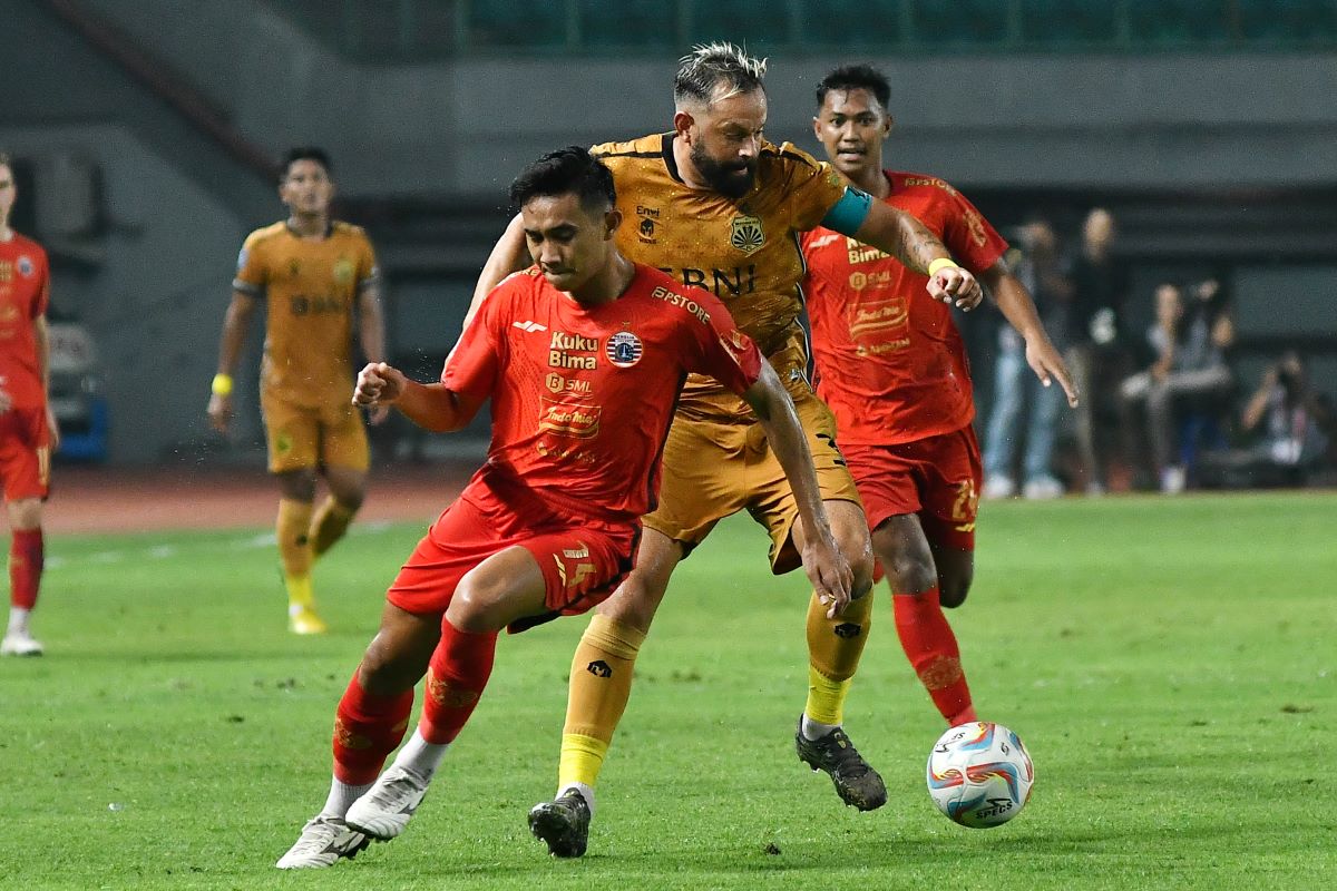 Bek Persija Jakarta sedang berebut bola dengan pemain lawan.