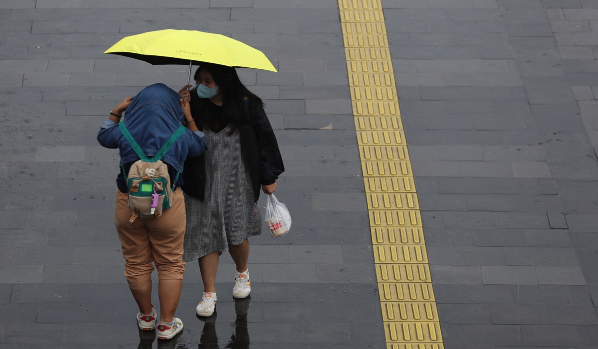 Pekerja menggunakan payung menghiindari guyuran hujan di kawasan Sudirman, Jakarta.