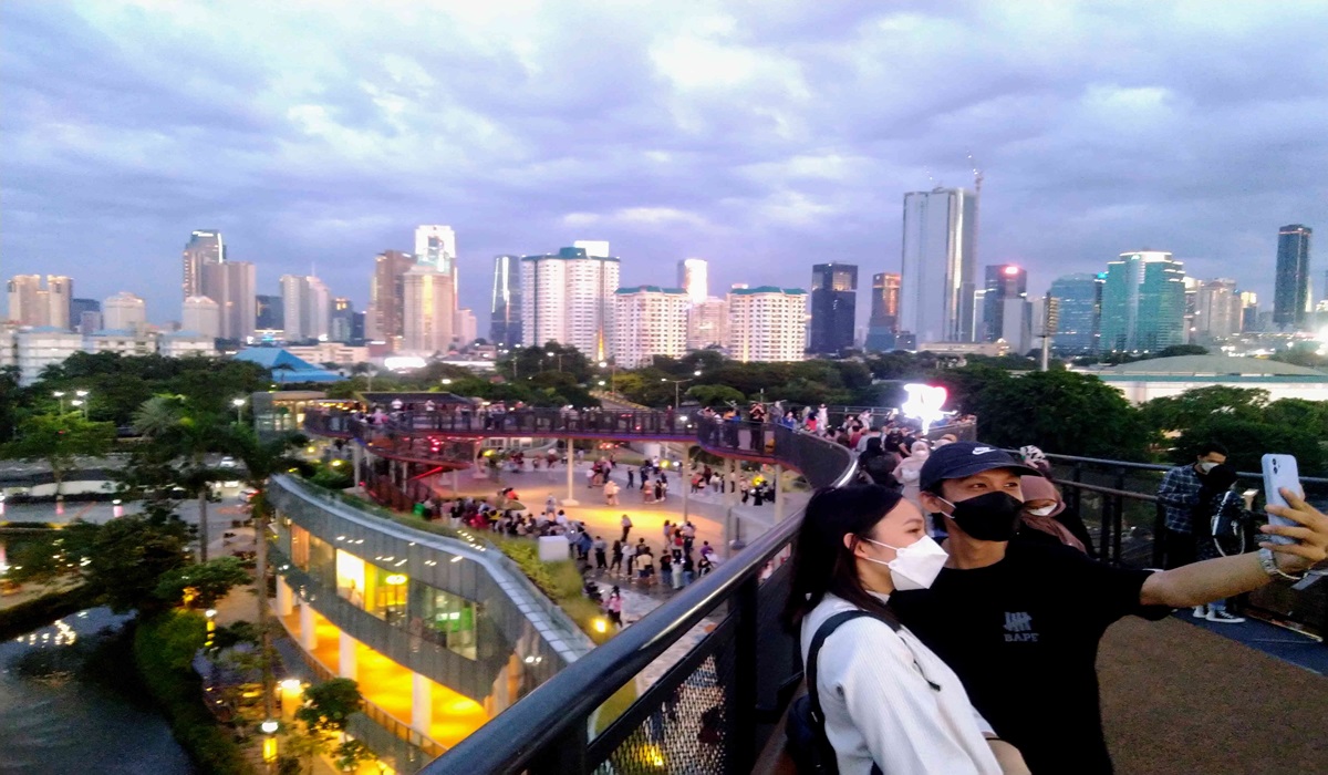 Warga menikmati suasana sore hingga matahari terbenam sambil berfoto dengan latar belakang gedung-gedung bertingkat di Jakarta.