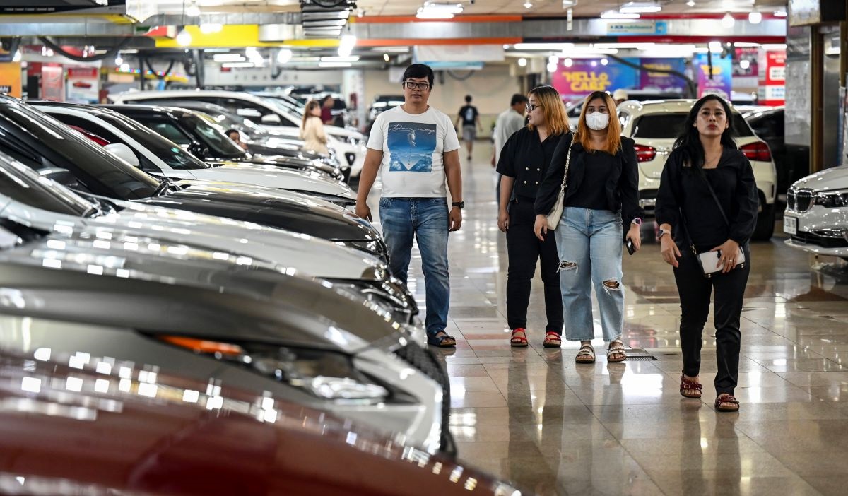 Sejumlah pengunjung melintas di samping deretan mobil bekas yang dijual di Bursa Mobil WTC Mangga Dua, Jakarta, Jumat (29/3/2024).