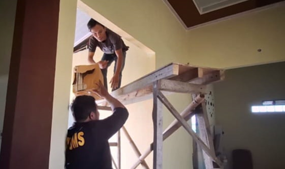 Tersangka nengambil rokok ilegal yang disembunyikan di atas atap rumah.