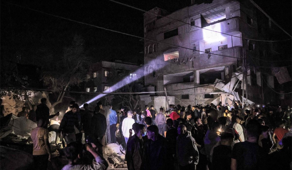 Orang-orang berkumpul di sekitar gedung yang terkena pemboman Israel di Rafah di Jalur Gaza selatan pada 7 Mei 2024.