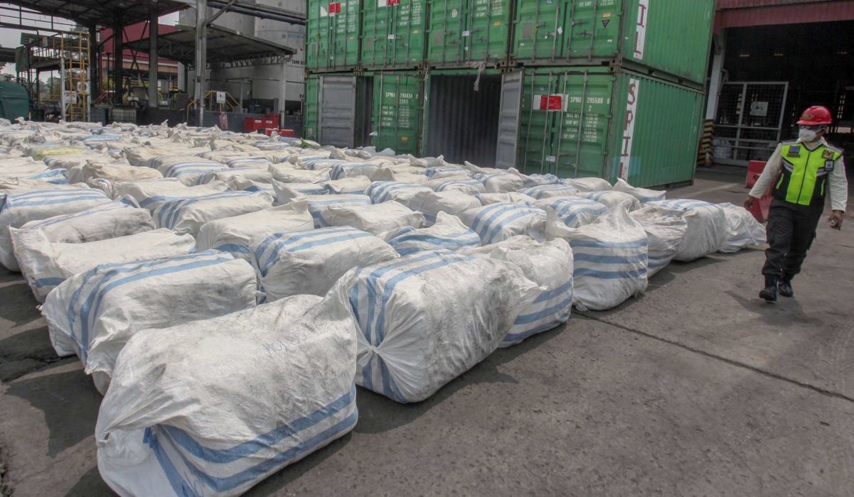 Petugas melintas di dekat barang bukti pakaian bekas impor ilegal sebelum dimusnahkan.