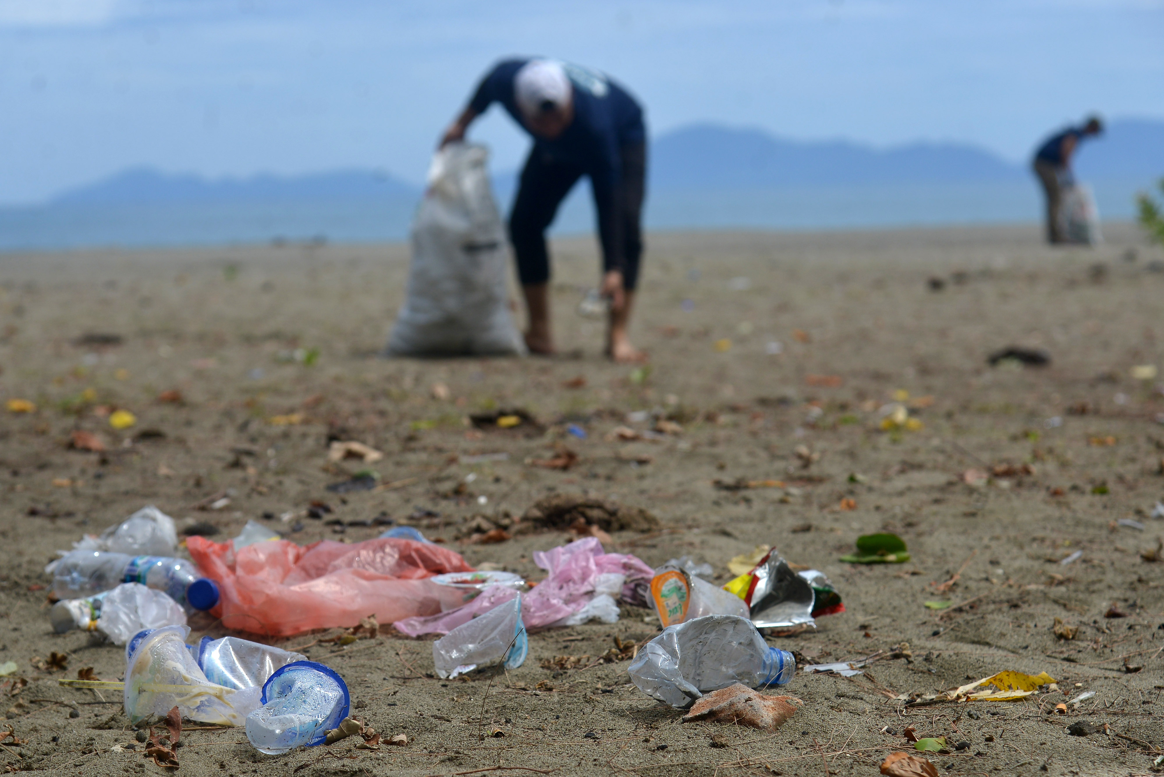 Warga yang tergabung dalam komunitas lingkungan memungut sampah botol plastik bekas