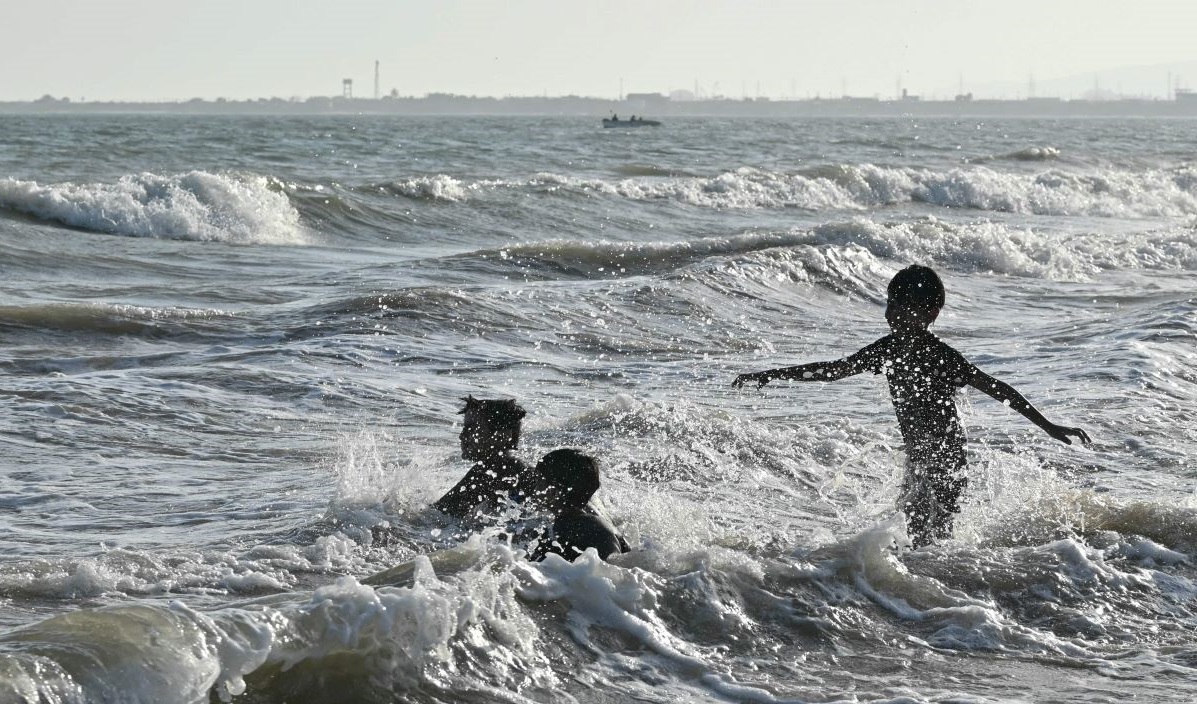 Orang-orang yang bersuka ria berenang di sepanjang tepi laut Arab saat mereka mendinginkan diri pada malam musim panas yang terik.