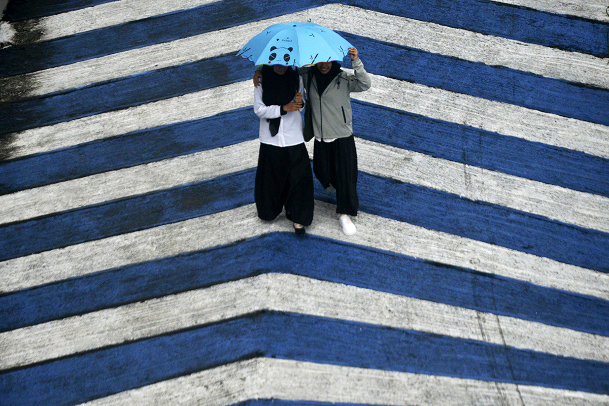 Warga menggunakan payung saat hujan di Makassar, Sulawesi Selatan, Senin (10/10/2022).