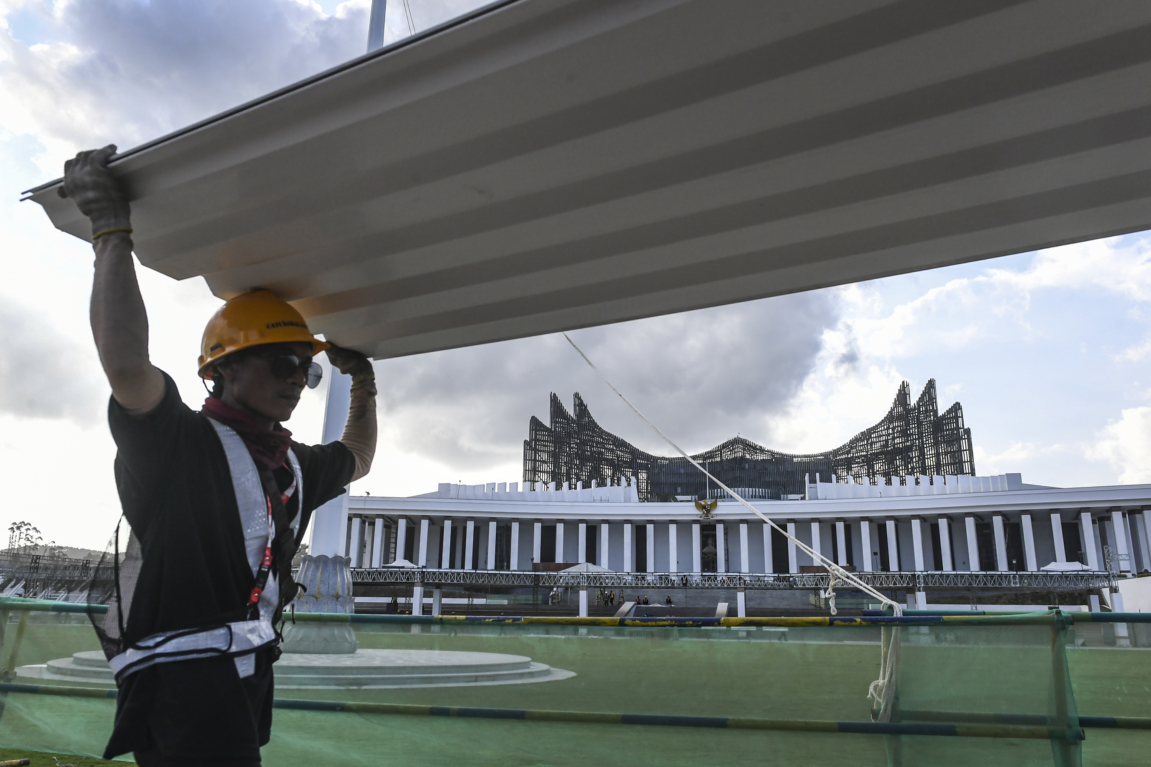 Pekerja membawa atap tenda yang akan dipasang untuk upacara HUT RI di Lapangan Upacara Istana Kepresidenan IKN