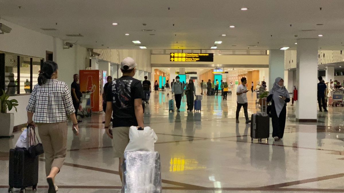 Para penumpang pesawat berjalan di bandara.