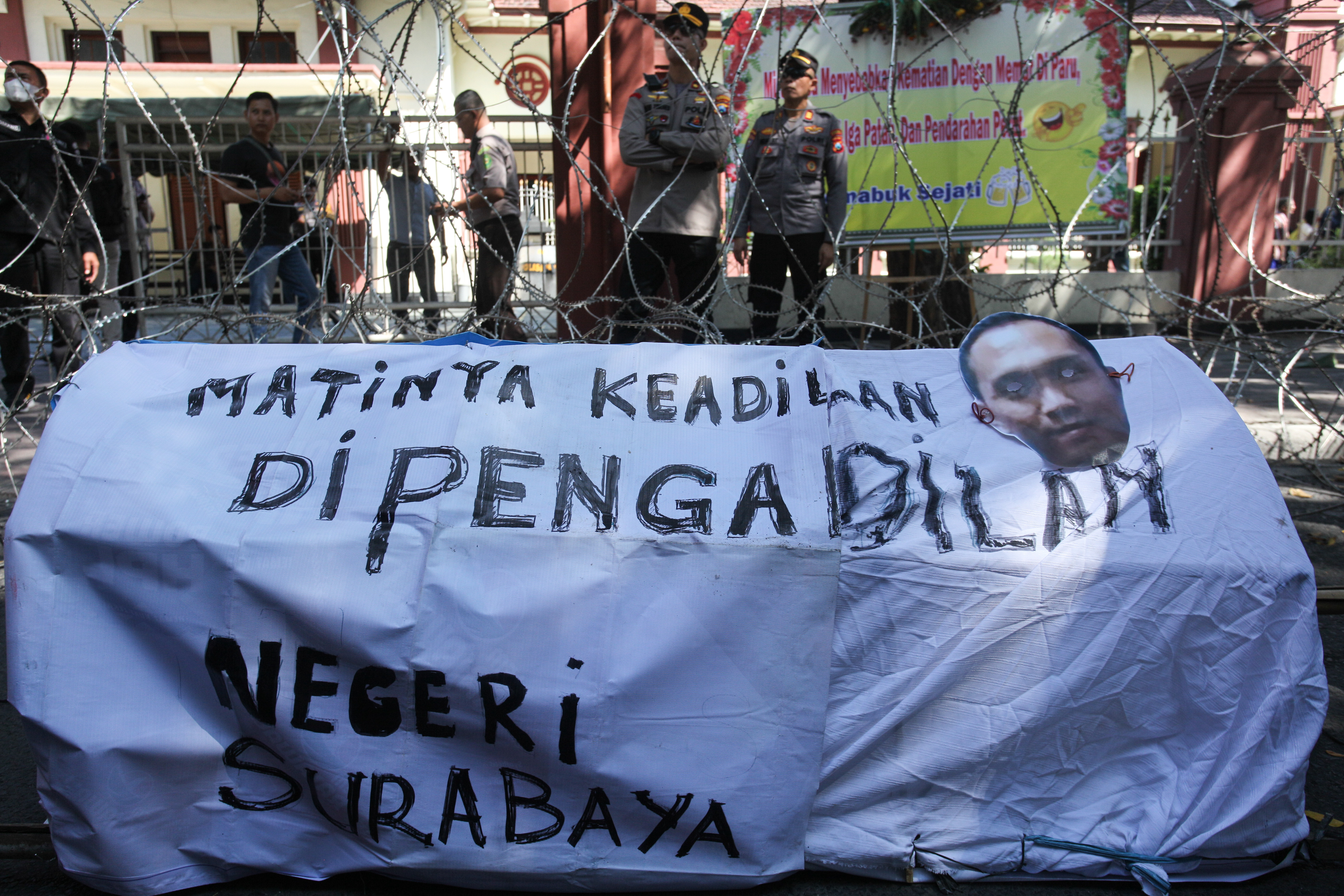 Polisi bersiaga saat sekelompok orang berunjuk rasa di depan Gedung Pengadilan Negeri Surabaya, Jalan Arjuno, Surabaya, Jawa Timur.